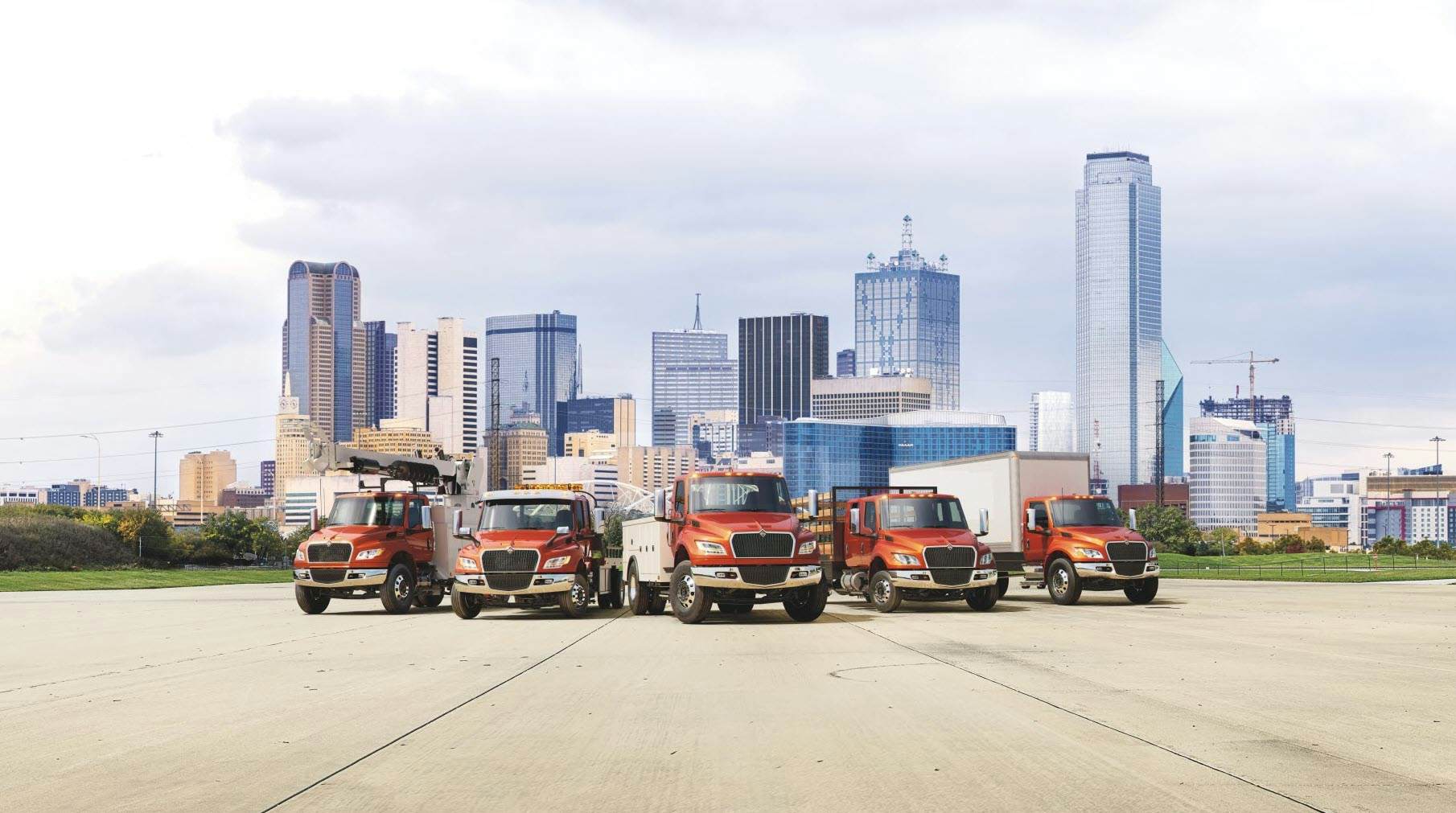 A group of trucks parked in front of a city