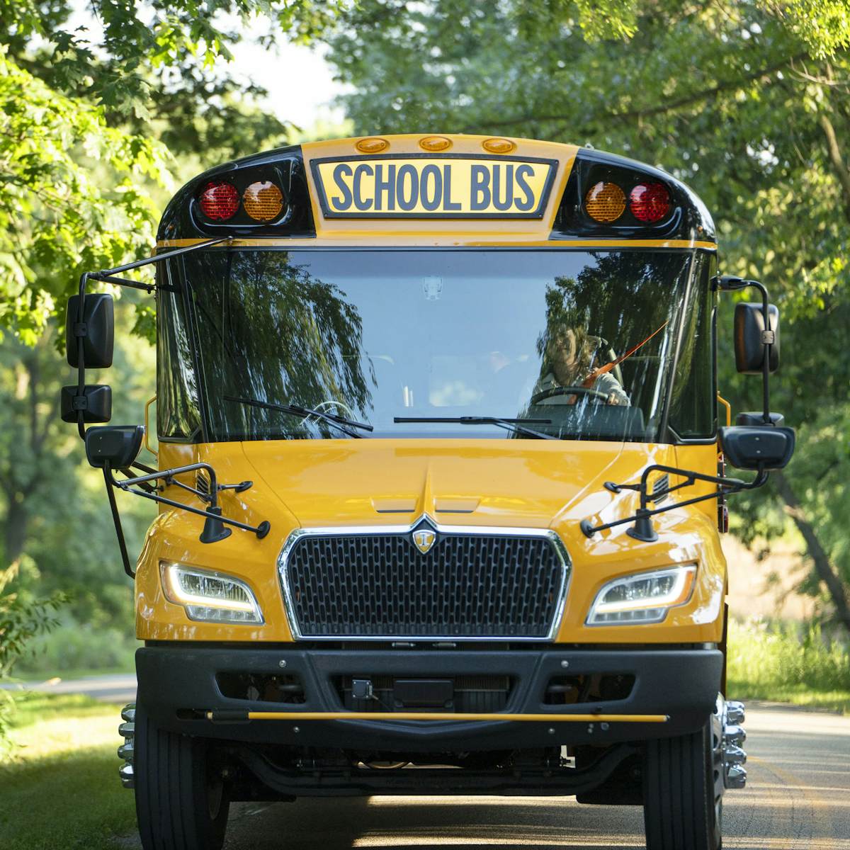 Bus driving down wooded road
