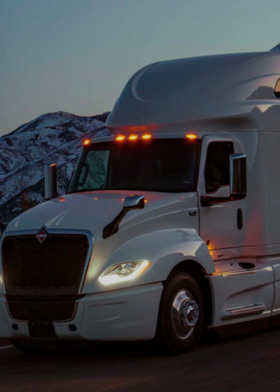 Truck driving along a road with snowy mountain background