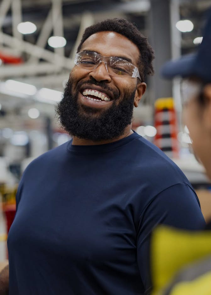 A person wearing safety glasses and smiling at another person