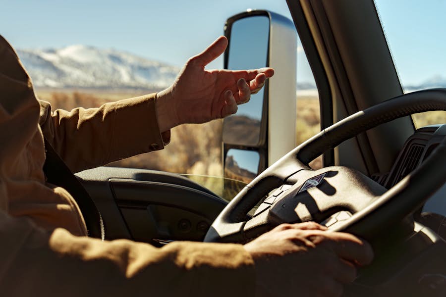 A person driving a truck with snowy mountains in the background