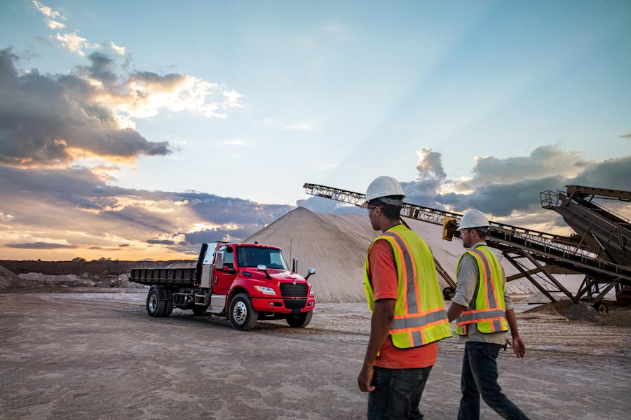 A group of men in safety vests walking in front of a truck