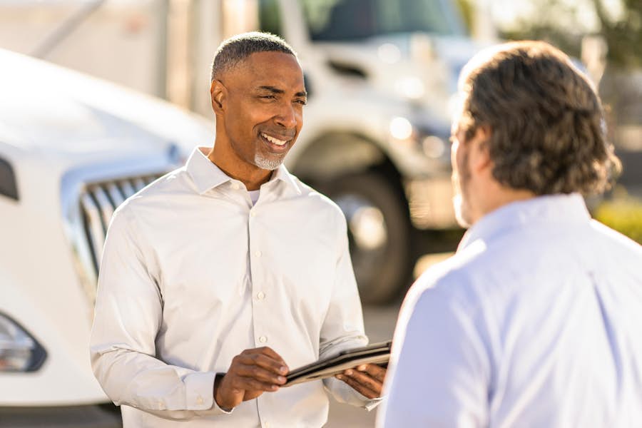 A person holding a clipboard and another person talking
