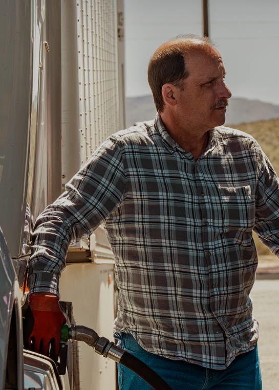 Truck driver filling a truck with fuel at a gas station